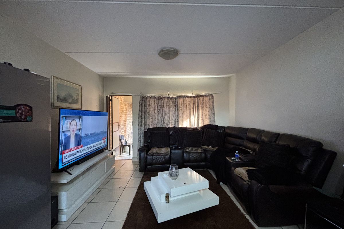 A living room featuring tiled flooring and a built-in media console, providing a functional space with direct access to an outdoor area.