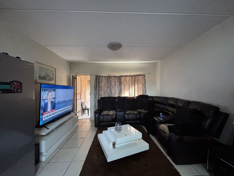 A living room featuring tiled flooring and a built-in media console, providing a functional space with direct access to an outdoor area.