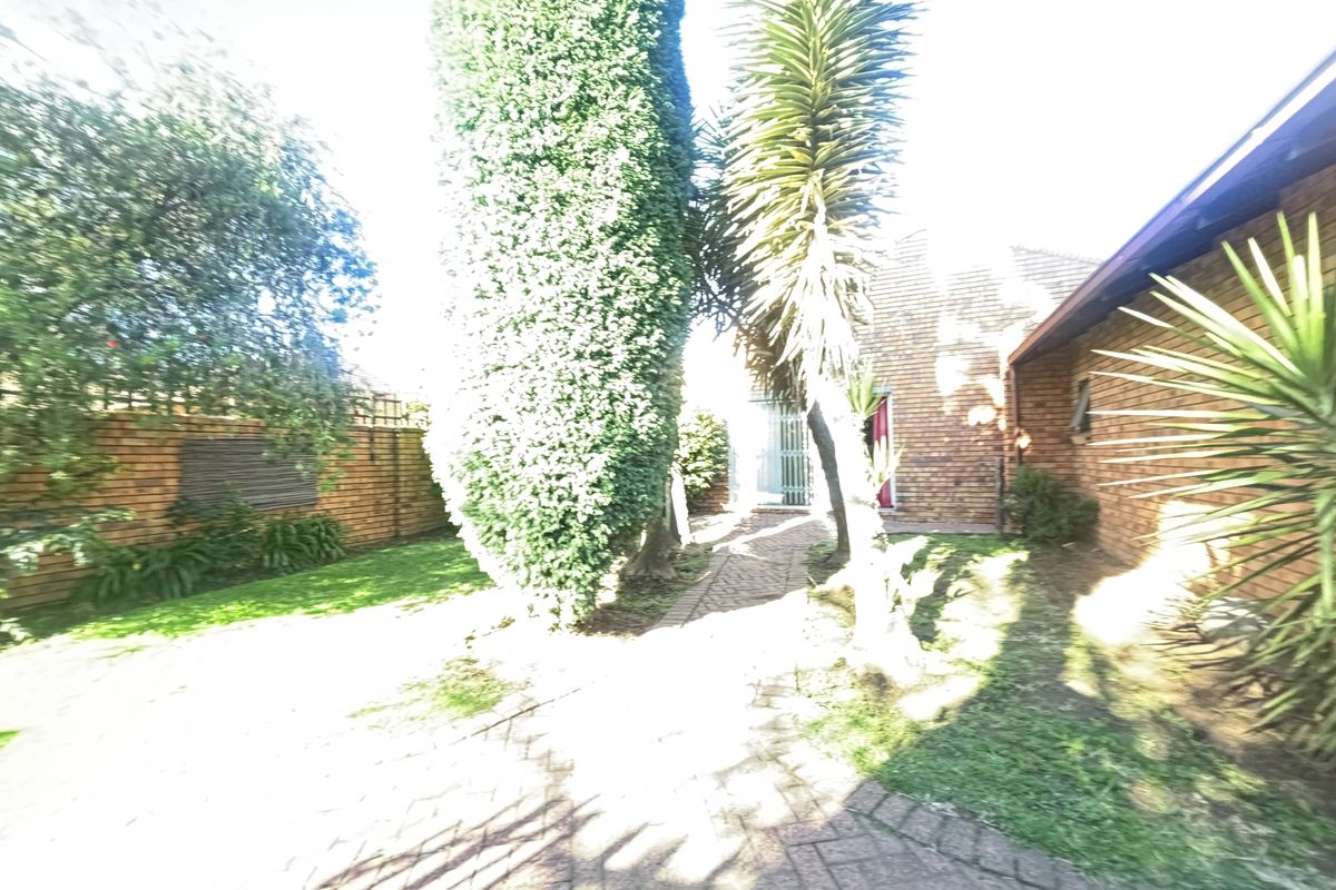 A private rear garden area featuring brick paving, established trees, and a brick boundary wall, providing a secluded outdoor space.