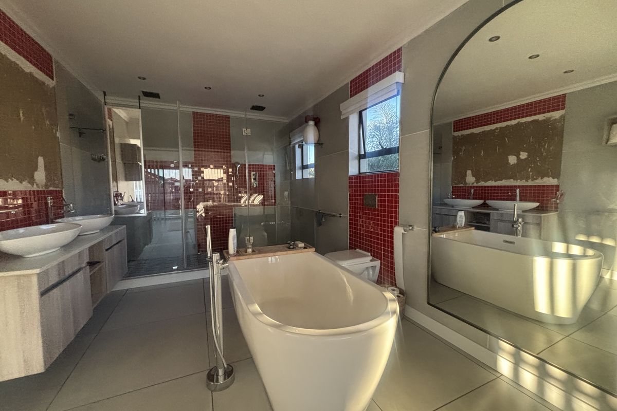 Spacious bathroom featuring a freestanding tub, double vanity, and glass shower, currently requiring wall repairs and finishing to complete the space.