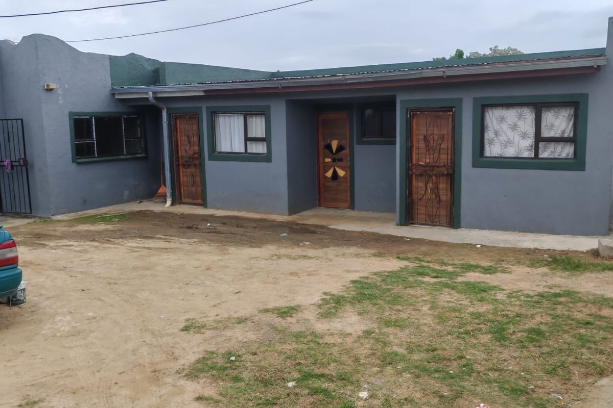 Front elevation of a single-story residential property featuring painted masonry walls, multiple entrance doors with security gates, and aluminium window frames.