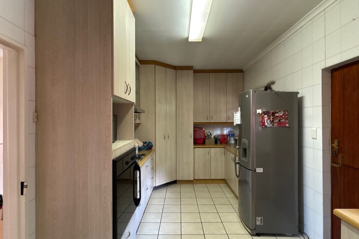 A functional kitchen featuring light-toned built-in cabinetry, laminate countertops, built-in oven, and ceramic tiled flooring and walls.