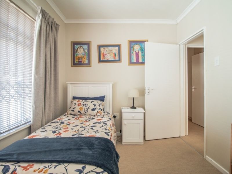 A cozy, well-maintained bedroom featuring neutral wall tones, carpeted flooring, and a window with fitted blinds, offering a comfortable and functional living space.