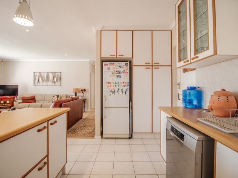 Open-plan kitchen and living area featuring tiled flooring, built-in cabinetry, and laminate countertops, creating a functional and connected living space.