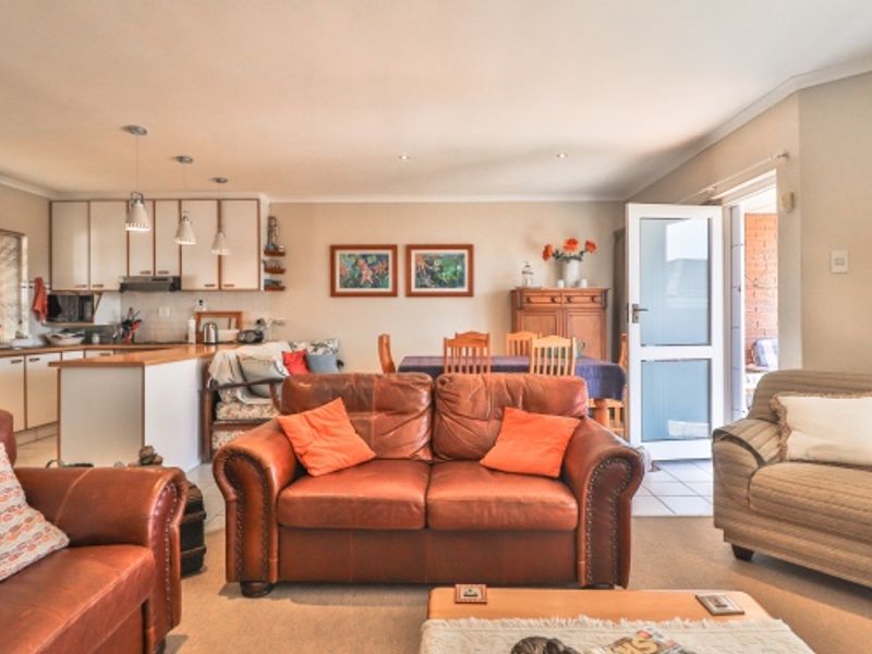 Spacious open-plan living and dining area featuring a functional kitchen with built-in cabinetry and direct access to an outdoor patio space.