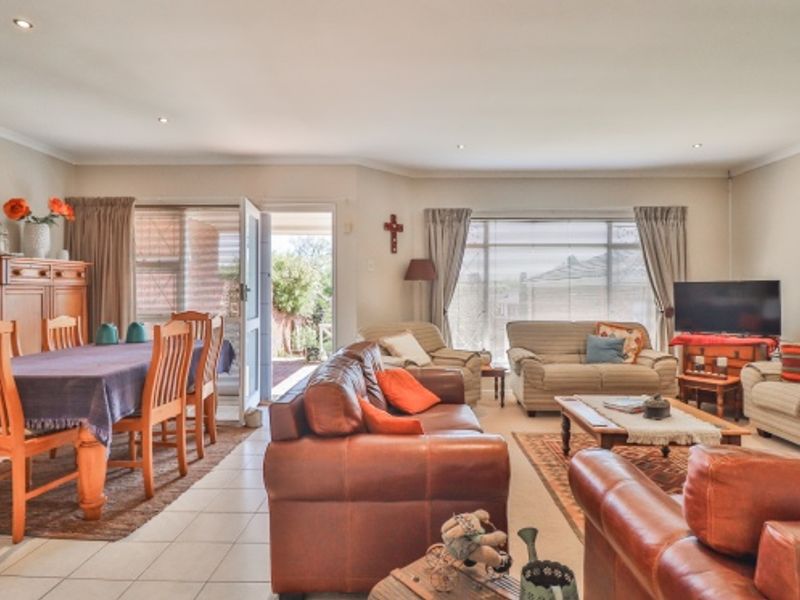 Spacious open-plan living and dining area featuring tiled flooring, recessed downlights, and direct access to an outdoor patio through a sliding glass door.