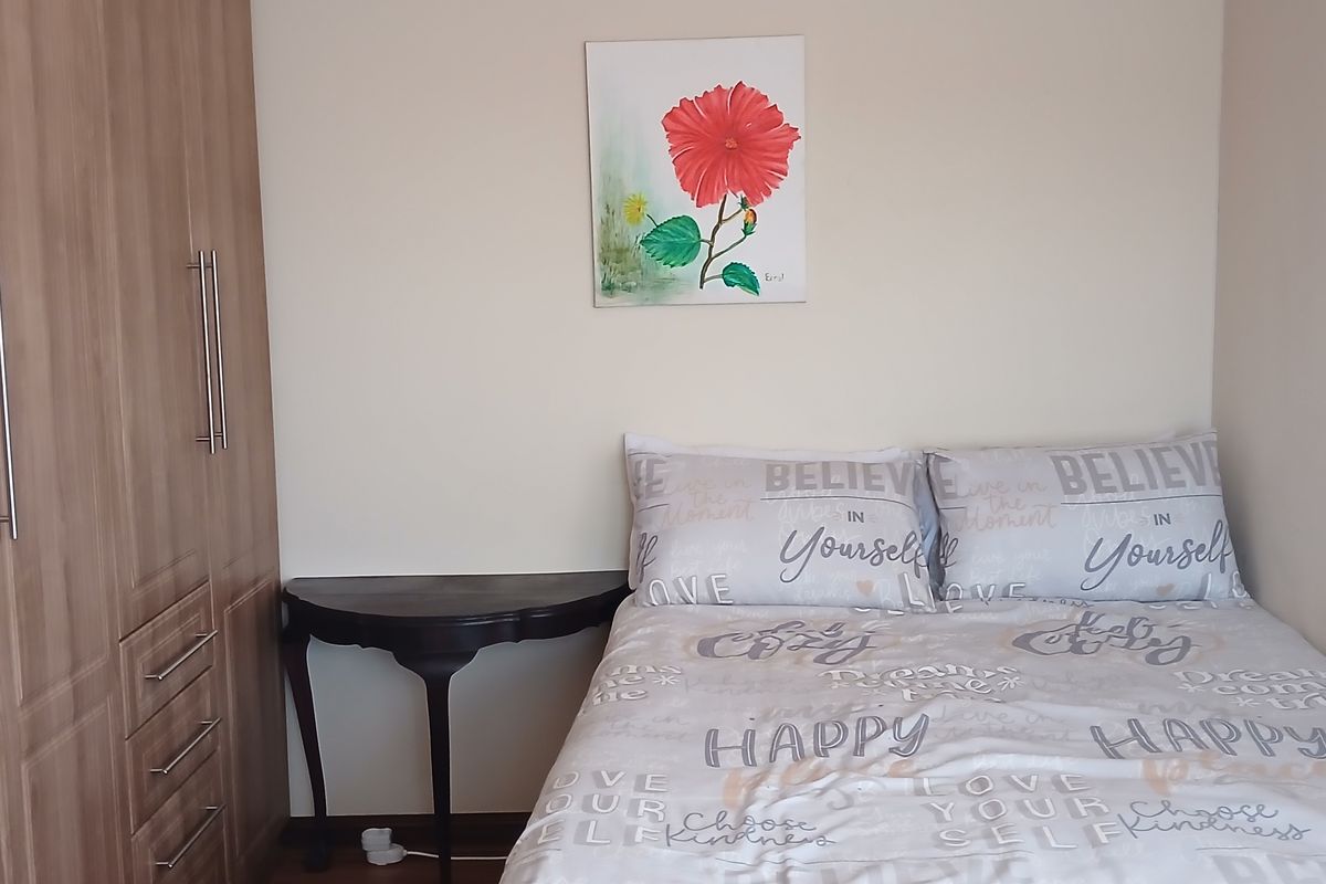 A cozy bedroom featuring a built-in wardrobe with wood-grain finish and laminate flooring.