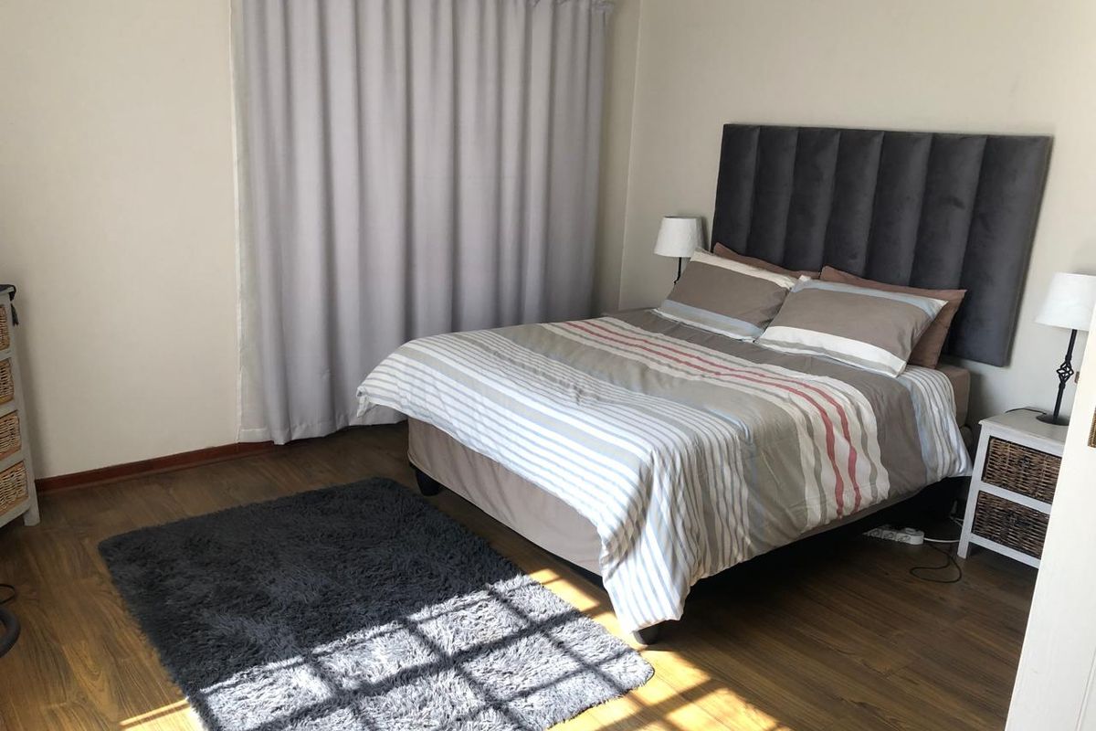 A well-maintained bedroom featuring laminate flooring and neutral wall finishes, providing a comfortable and functional living space.