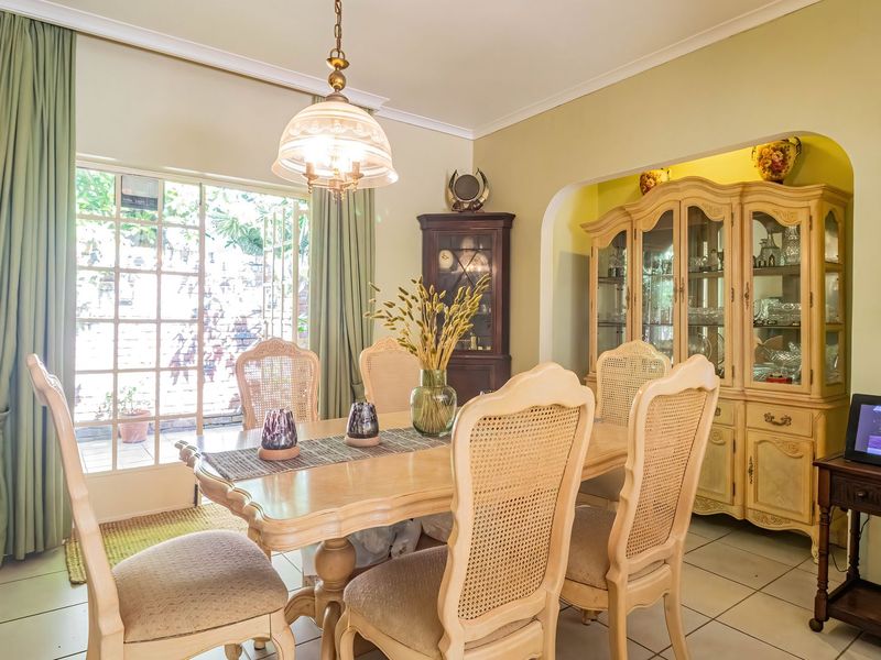 A dining room featuring tiled flooring, a central pendant light, and a glass sliding door providing access to the outdoor area.