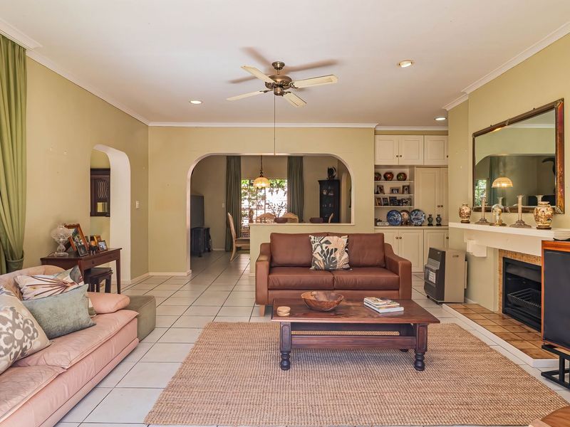 Spacious open-plan living area featuring tiled floors, a central fireplace, built-in cabinetry, and an archway leading to the adjacent dining space.