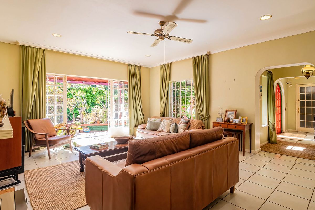 Spacious living room featuring tiled flooring, recessed lighting, a ceiling fan, and large french doors providing direct access to the garden area.