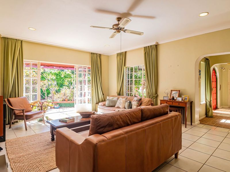 Spacious living room featuring tiled flooring, recessed lighting, a ceiling fan, and large french doors providing direct access to the garden area.
