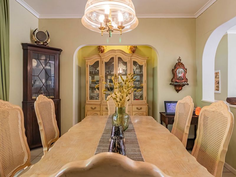 A traditional dining room featuring an arched entryway, tiled flooring, and a central pendant light fixture, creating a classic and defined dining space.
