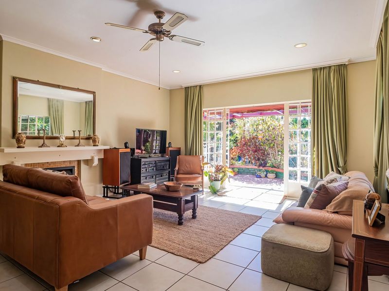 Spacious living room featuring a fireplace, ceiling fan, and tiled flooring, with direct access to the outdoor patio through large glass french doors.