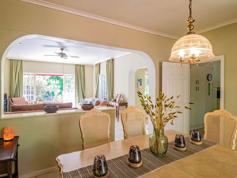 Open-plan dining and living area featuring a classic archway, tiled flooring, and a decorative pendant light, creating a connected and functional living space.