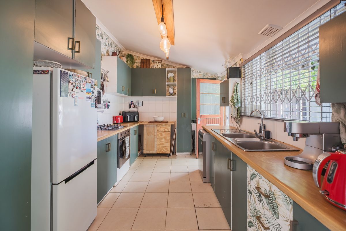 Functional kitchen featuring timber countertops, built-in cabinetry, gas cooktop, and a stainless steel double sink with natural light.