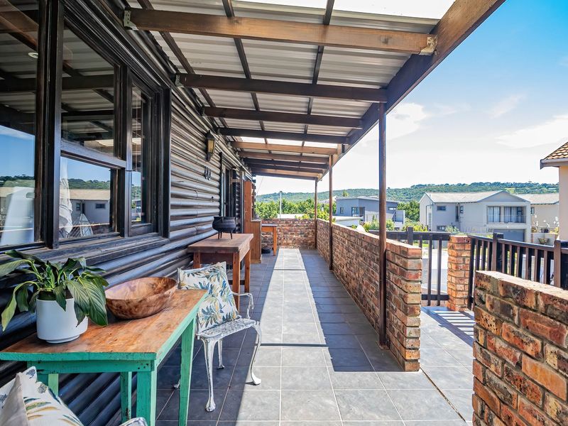 A spacious covered balcony featuring tiled flooring, brick balustrades, and timber wall cladding, offering an elevated outdoor living space.