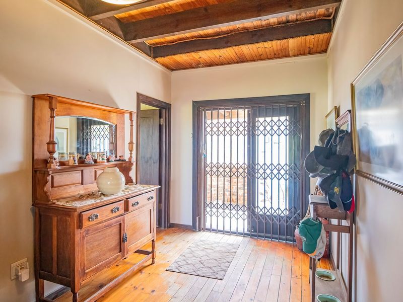 Welcoming entrance hall featuring warm timber flooring and a distinctive exposed timber beam ceiling, leading through a secure sliding door to the exterior.