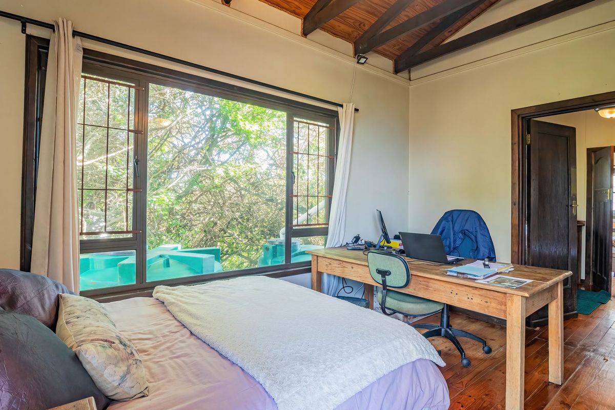 Bedroom featuring exposed timber ceiling beams, hardwood flooring, and a large window providing natural light and garden views.