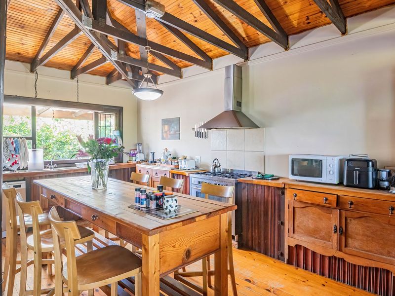 Open-plan kitchen and dining area featuring exposed timber beam ceilings, wooden cabinetry, and timber flooring, creating a rustic and functional living space.