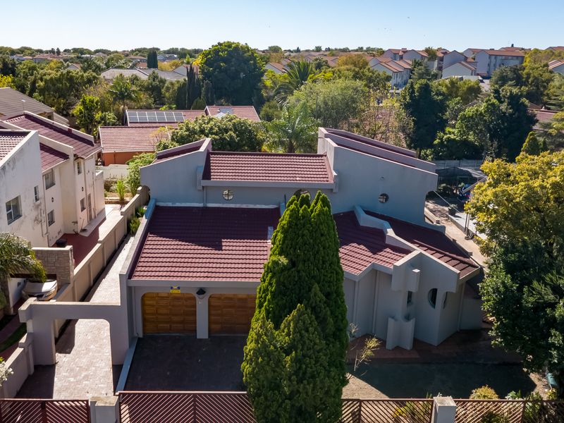 Aerial view of a residential property featuring a double garage, tiled roof, and paved driveway within a suburban neighborhood setting.