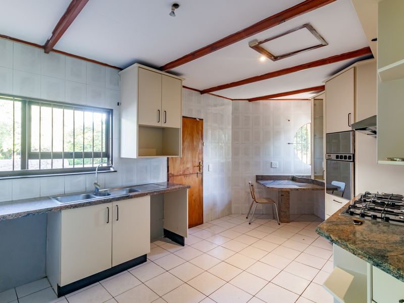 A dated kitchen featuring stone countertops, built-in oven, gas hob, and tiled finishes, offering significant potential for modernization and renovation.