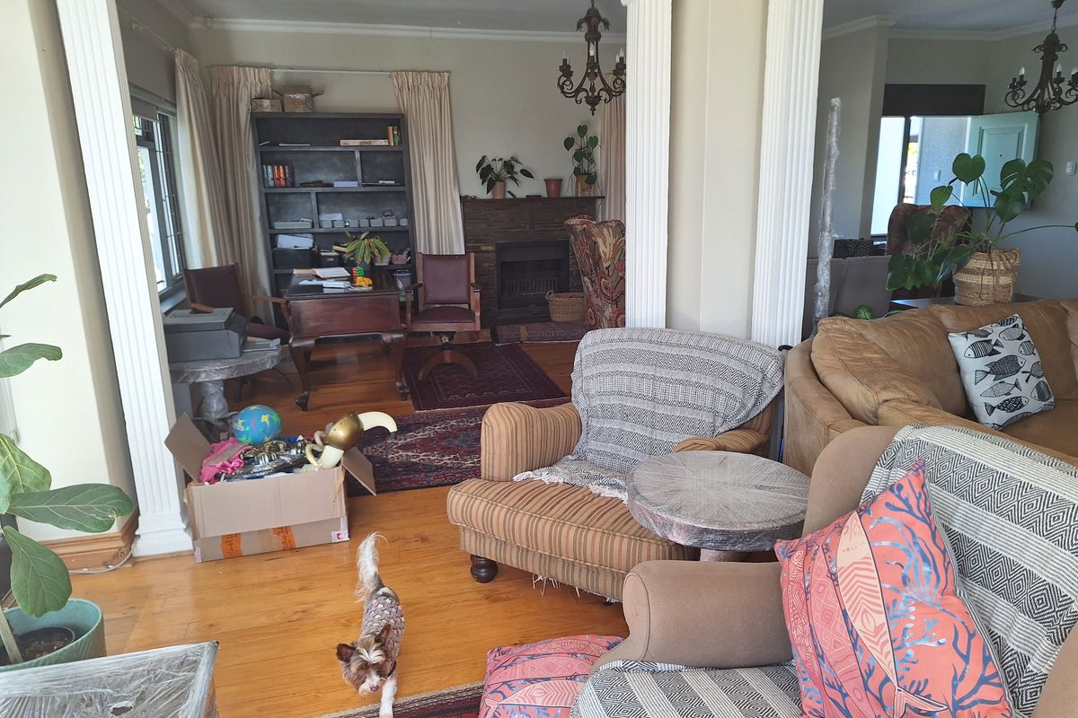 Spacious living area featuring hardwood flooring, a stone fireplace, and decorative columns, offering a classic layout with potential for modern updates.