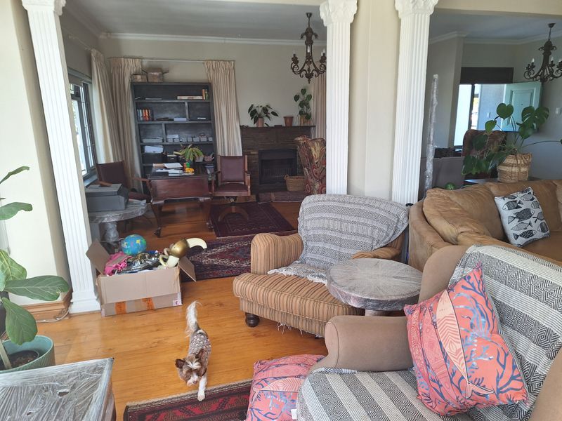 Spacious living area featuring hardwood flooring, a stone fireplace, and decorative columns, offering a classic layout with potential for modern updates.