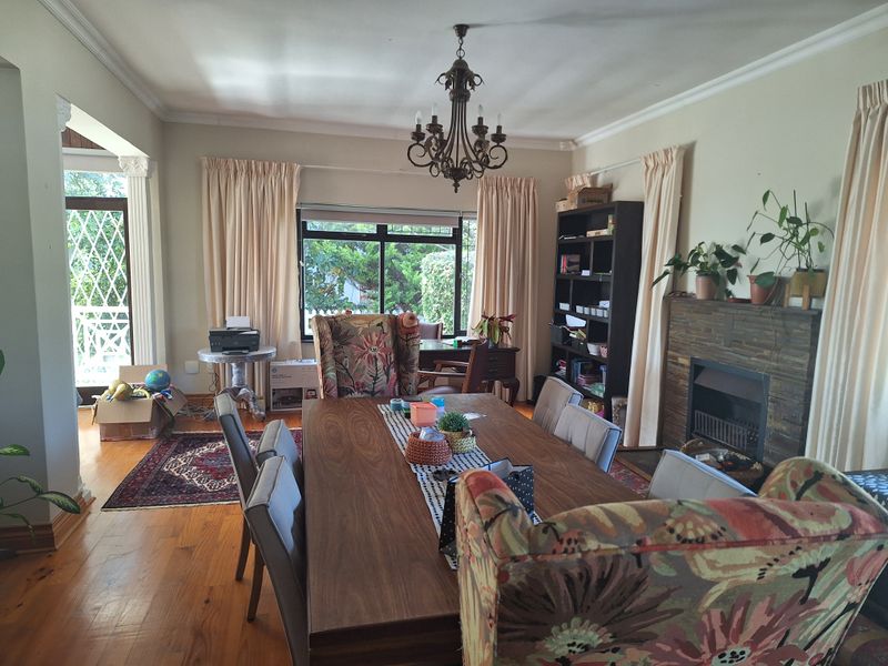 Spacious dining room featuring hardwood flooring, a stone-surround fireplace, and a classic chandelier, with direct access to an outdoor patio area.