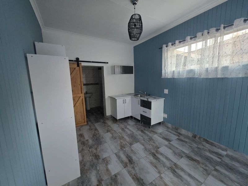 A compact kitchen area featuring modern cabinetry, tiled flooring, and a sliding barn door leading to an adjacent bathroom space.