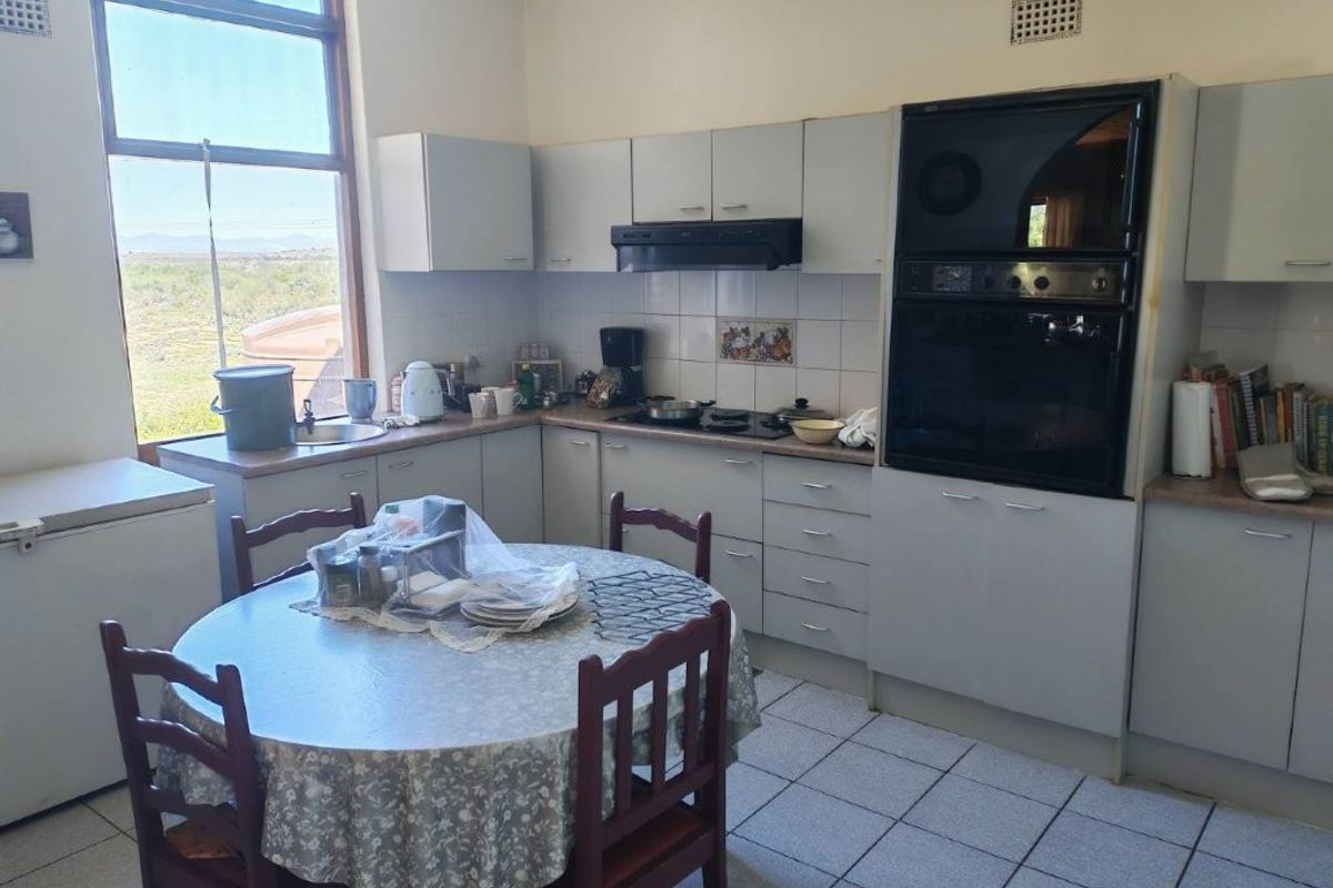 A functional kitchen featuring built-in cabinetry, integrated oven, extractor fan, and tiled flooring, with a large window providing natural light and landscape views.