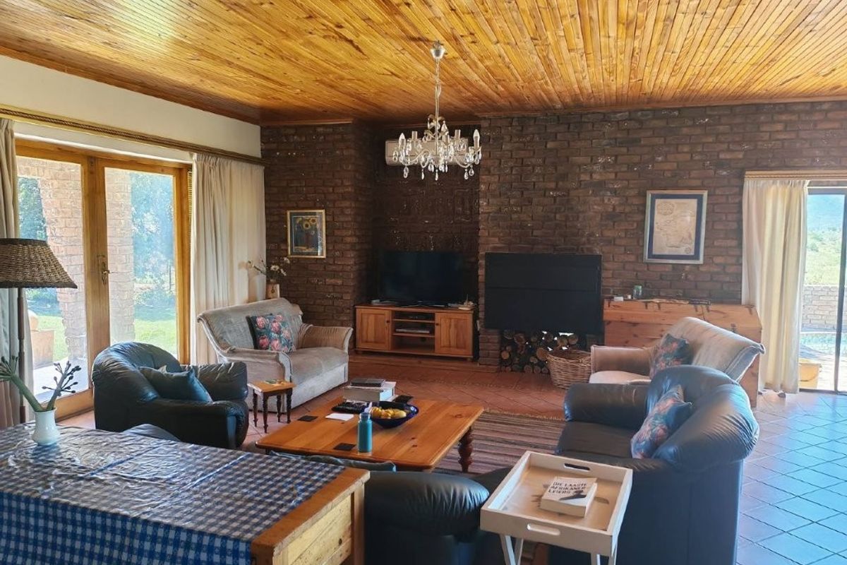 Spacious living room featuring a prominent exposed brick fireplace, warm timber ceiling, and large sliding doors providing natural light and garden access.