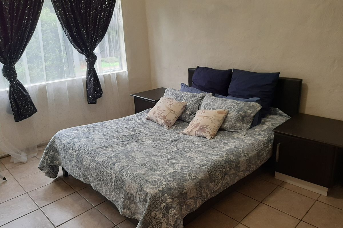 A functional bedroom featuring tiled flooring and a window with natural light, offering a neutral base for potential interior updates.