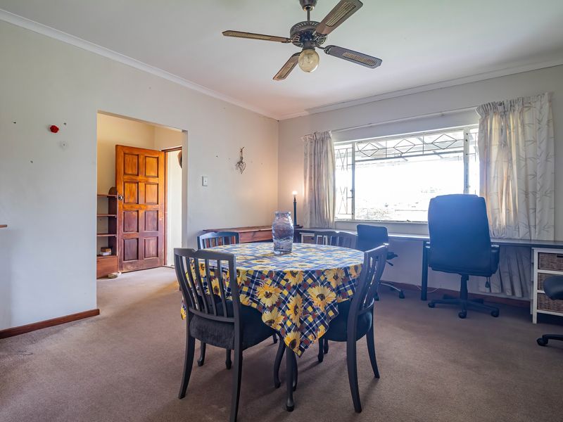 A multi-purpose living area featuring a ceiling fan, built-in desk space, and direct access to an adjacent room through a timber door.