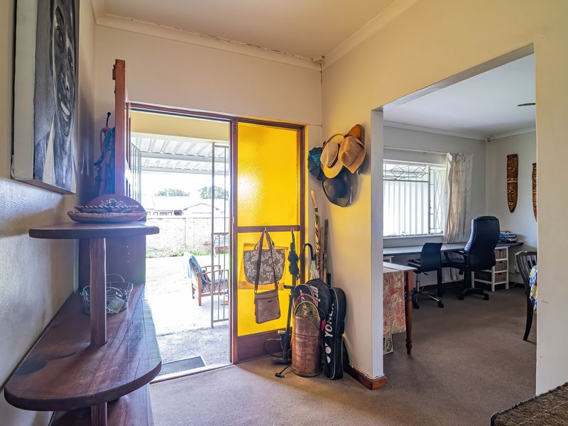 Entrance area featuring a distinctive yellow glass panel door, carpeted flooring, and direct access to an adjacent office space.