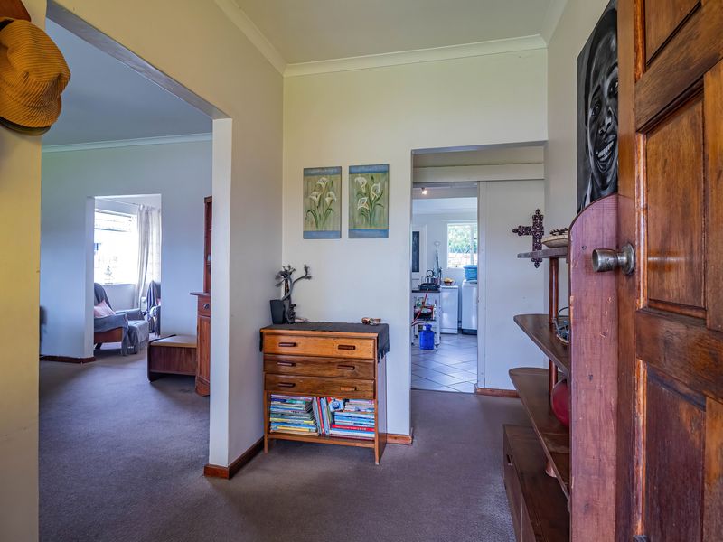 Entrance hallway featuring carpeted flooring, coved cornicing, and a solid wood door, providing access to the living area and kitchen.