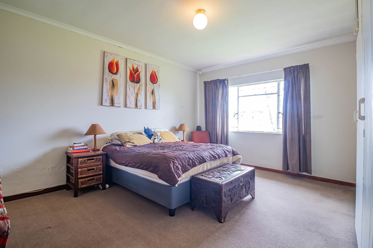 A spacious bedroom featuring neutral walls, carpet flooring, and a built-in wardrobe, offering a functional layout ready for modern updates.