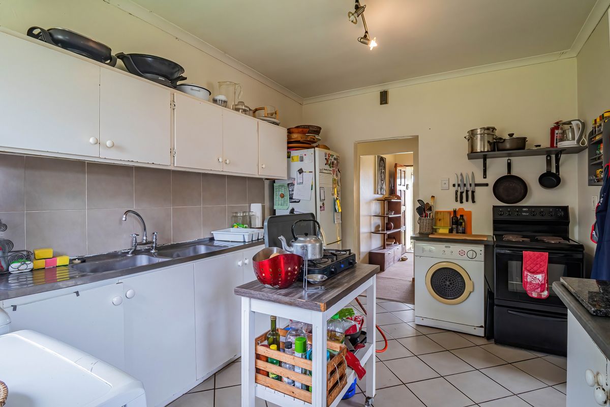 A functional kitchen featuring built-in cabinetry, a tiled backsplash, and tiled flooring, offering a practical layout with space for essential appliances.
