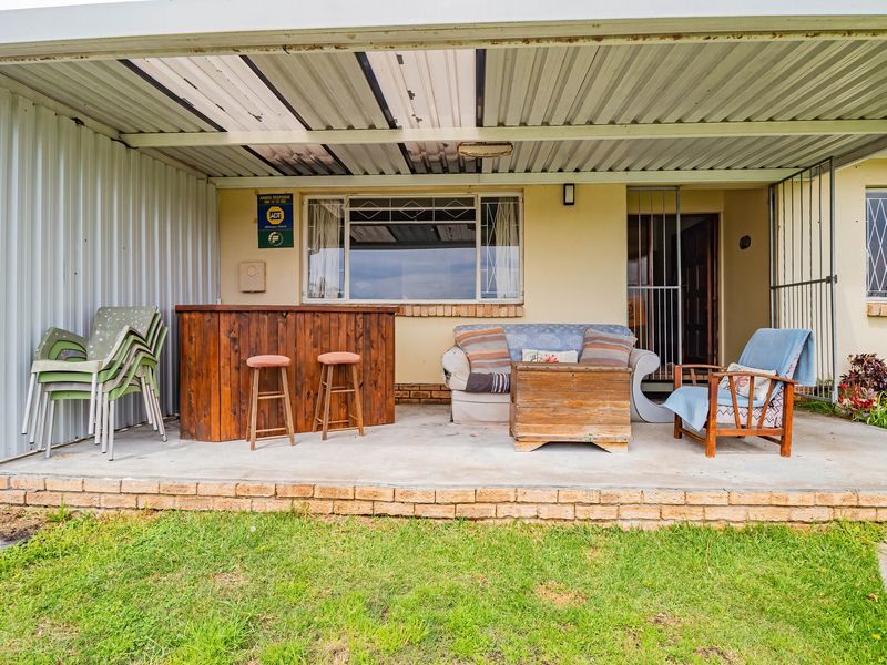 A covered outdoor patio area featuring a concrete floor, corrugated metal roofing, and security fixtures, providing a functional space for outdoor relaxation.
