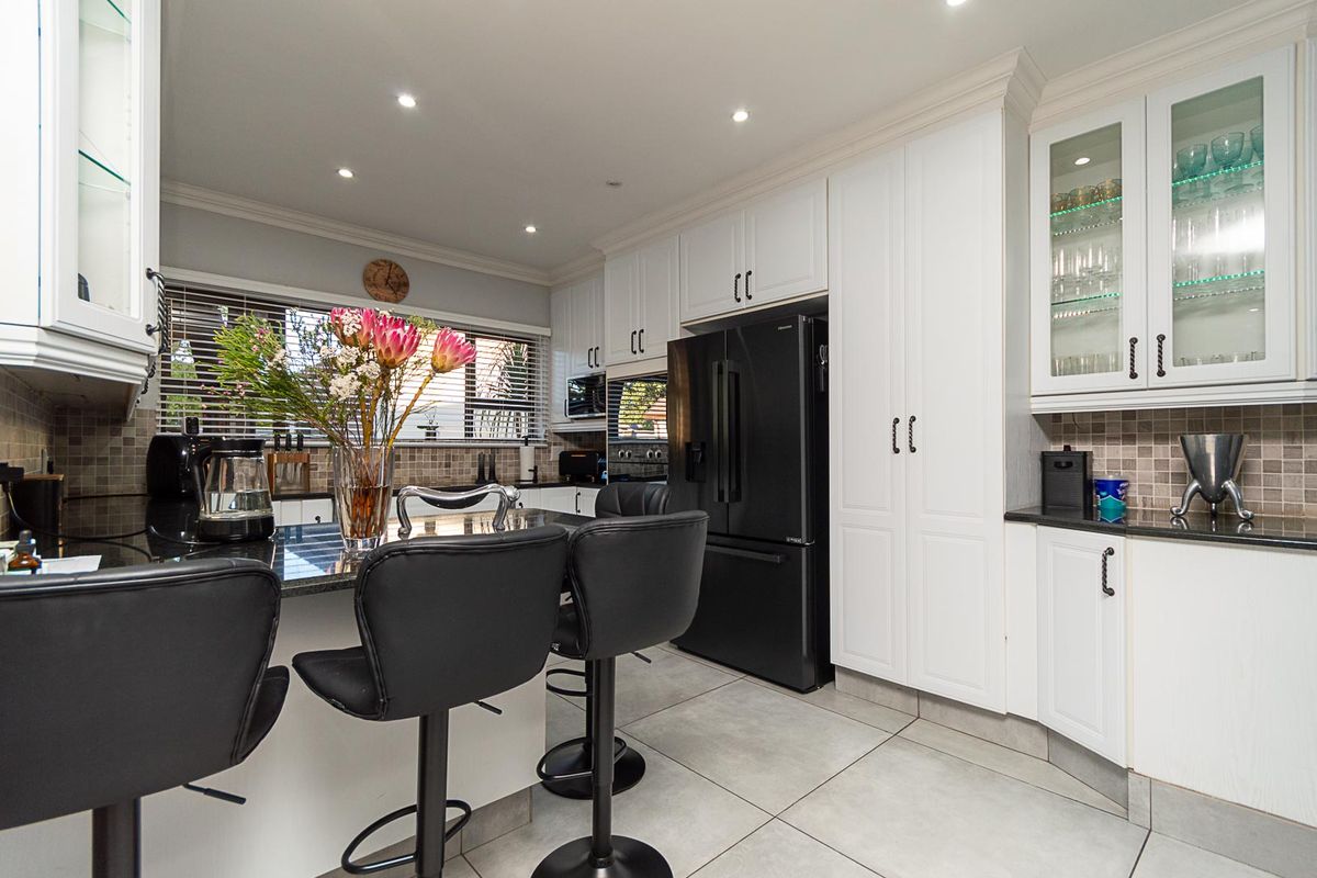Modern kitchen featuring white cabinetry, granite countertops, tiled backsplash, and recessed lighting, offering a clean and functional culinary space.
