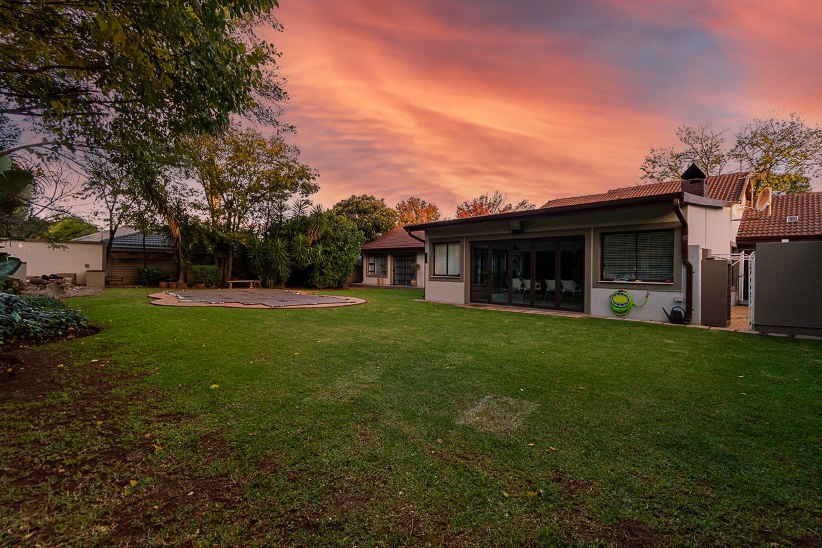 Spacious rear garden featuring a swimming pool with cover, well-maintained lawn, and direct access to the home via large sliding glass doors.