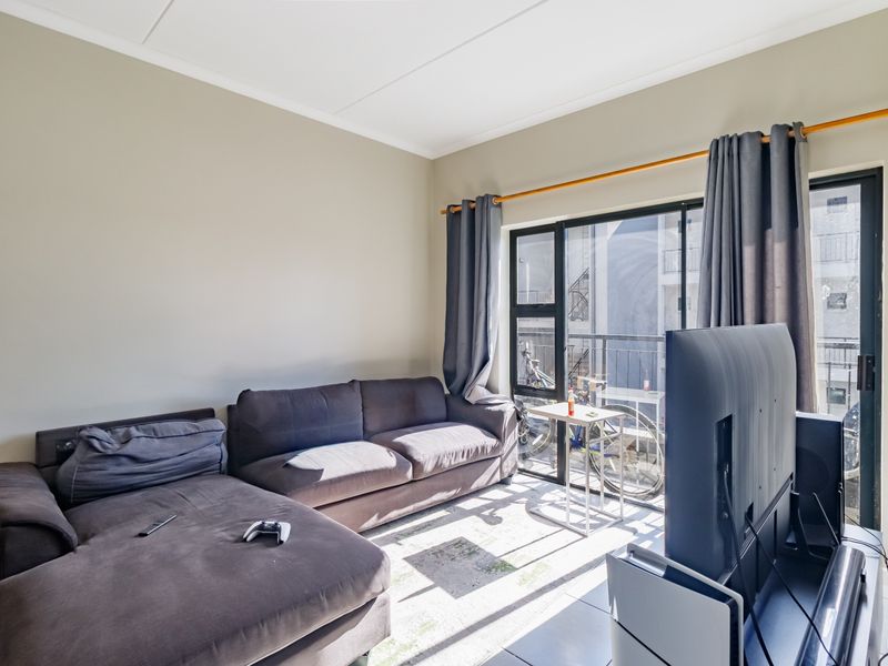 A living room featuring tiled flooring and a large sliding glass door providing access to a balcony area.