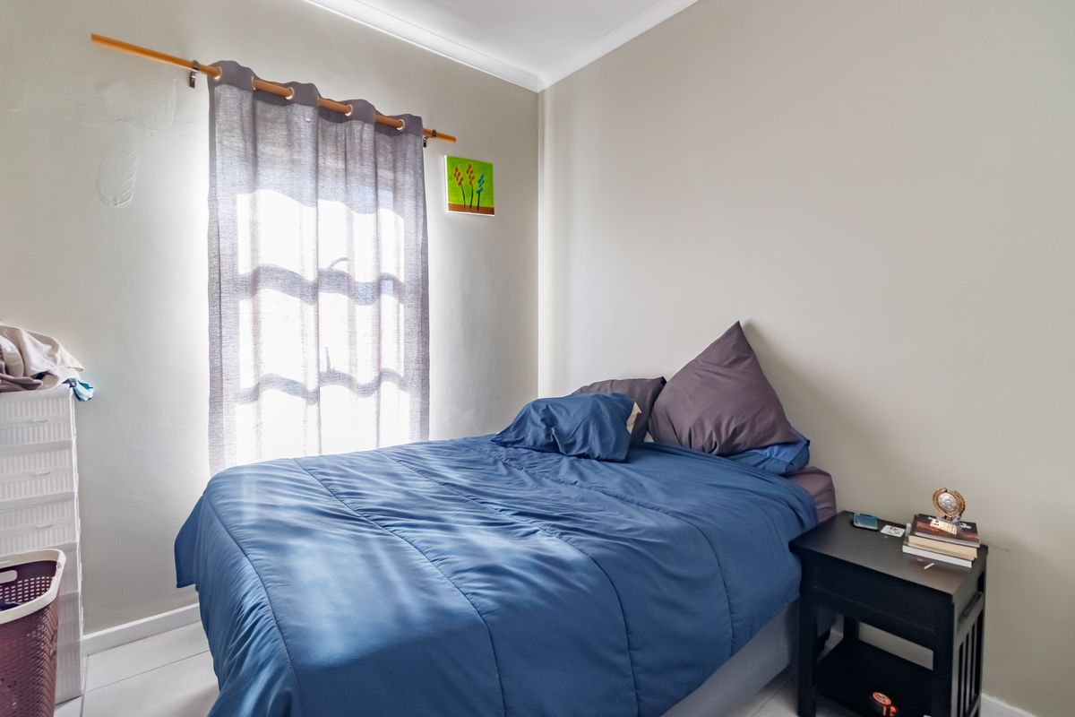 A functional bedroom featuring neutral wall finishes and a window with a curtain rod, providing natural light to the space.