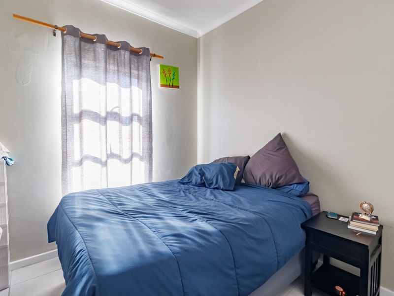 A functional bedroom featuring neutral wall finishes and a window with a curtain rod, providing natural light to the space.