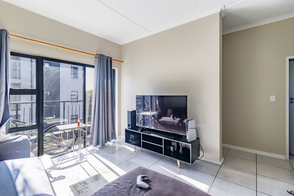 A bright living room featuring tiled flooring and a large sliding glass door providing access to a private balcony.