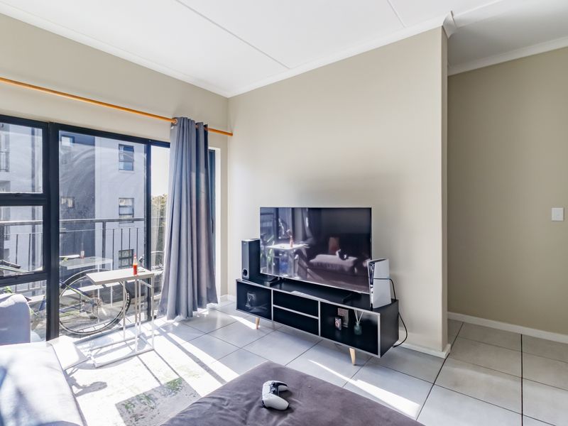 A bright living room featuring tiled flooring and a large sliding glass door providing access to a private balcony.