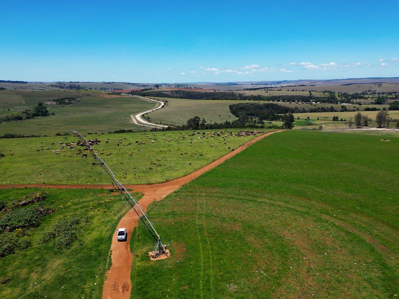 Aerial view of a large farm property featuring expansive grazing pastures, dirt access roads, and a center pivot irrigation system.