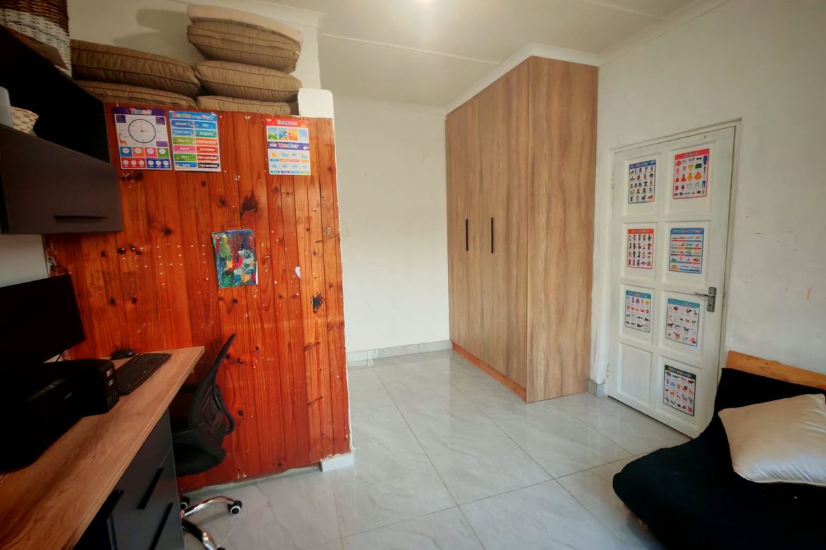 Bedroom featuring tiled flooring, built-in wooden wardrobe, and timber wall paneling. The space offers functional storage and neutral finishes.