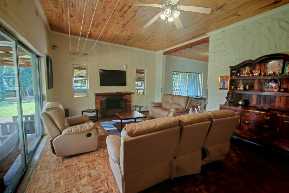 Spacious living room featuring a timber ceiling, brick fireplace, and parquet flooring, with large sliding glass doors providing access to the garden.