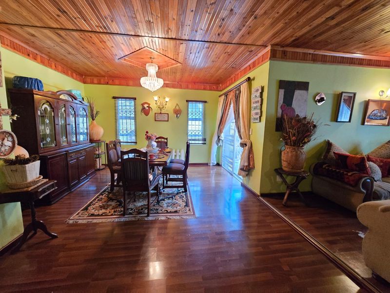 Open plan living and dining area featuring warm timber tongue and groove ceilings, laminate flooring, and direct access to the outdoors via sliding doors.